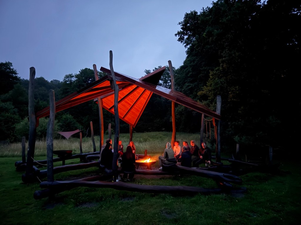 A group of people sitting at a campfire as night falls