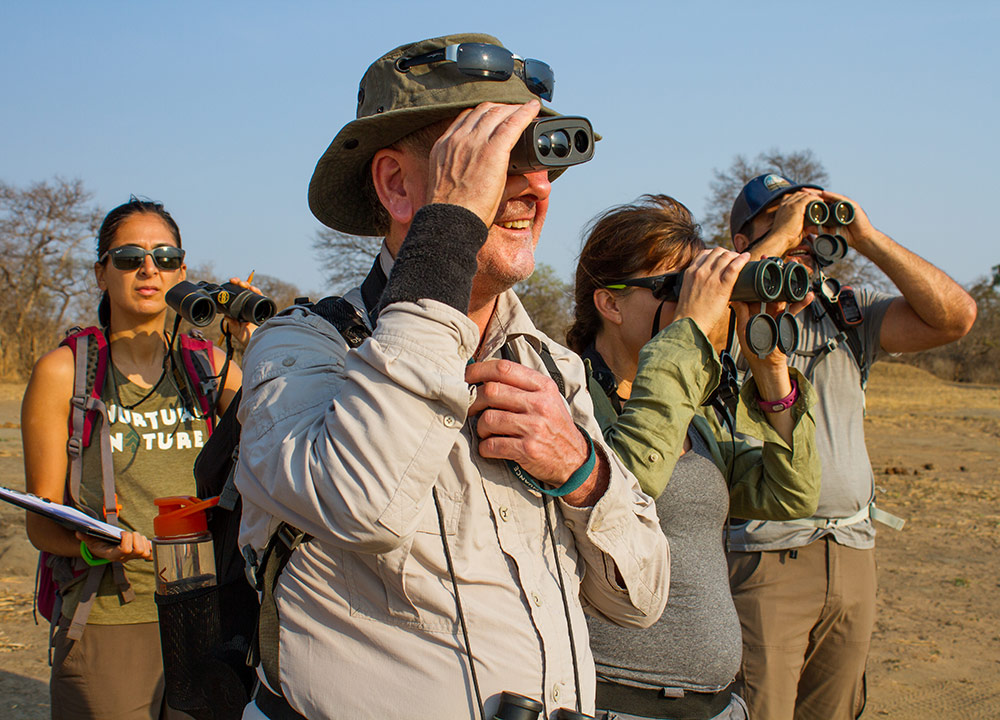 4 people in an arid landscape looking through binoculars