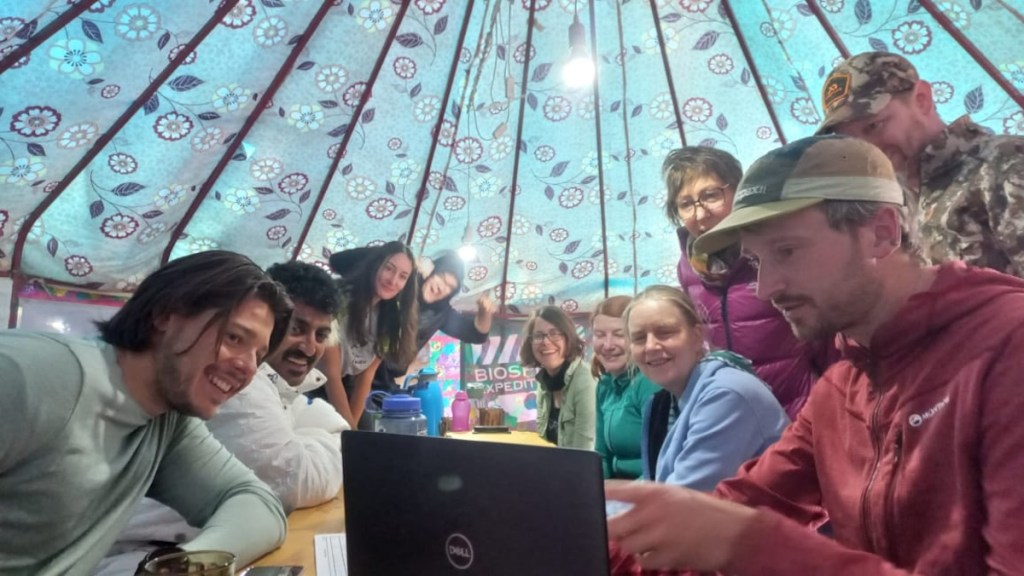 People gathered round a laptop in a yurt